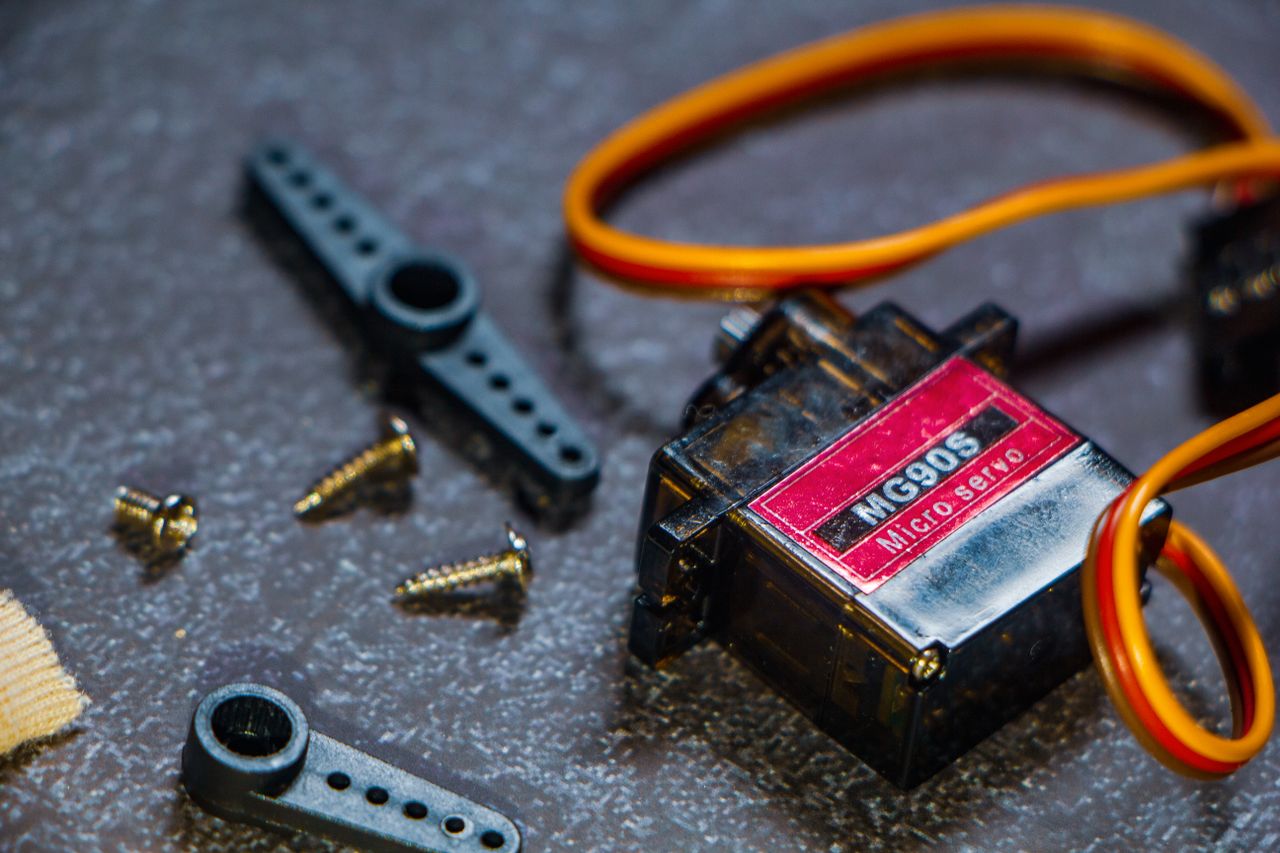 About Detailed view of an MG90S micro servo motor with screws and components for robotics applications.