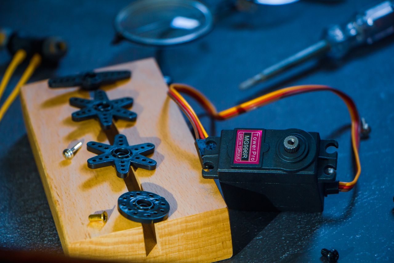 Services A servo motor and gear set on a wooden block, perfect for robotics enthusiasts and engineers.