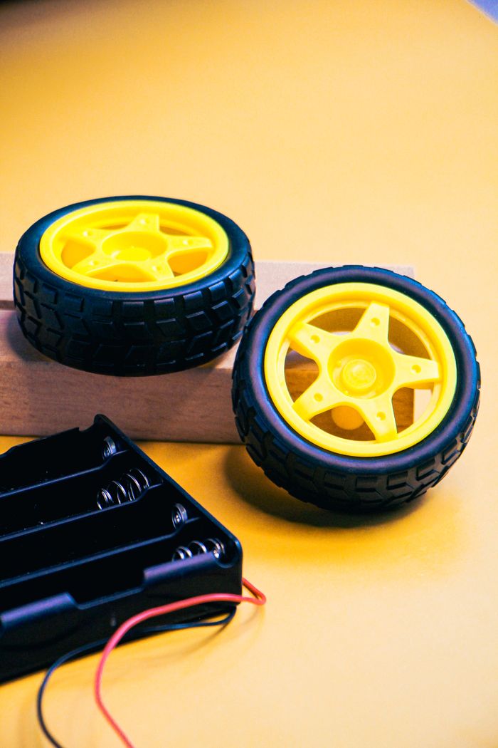 Services Close-up of robotics kit components with yellow wheels on a vibrant yellow background.