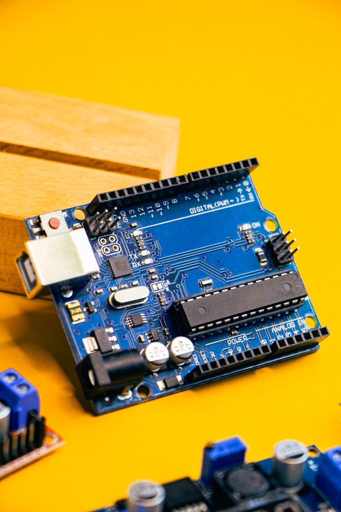 Services Close-up of an Arduino microcontroller on a vibrant yellow background, showcasing electronic innovation.