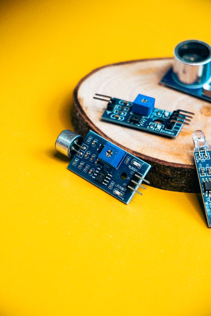 Services Close-up of robotics components on a vibrant yellow background with wooden base.