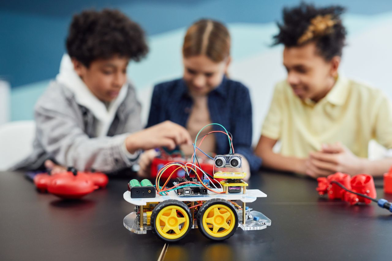 Services Children collaborating on a robotics project, building a small robot car in an educational setting.